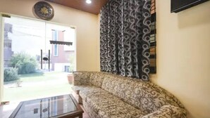 Un salon avec un canapé à motifs, une table basse en verre et un rideau à motifs.