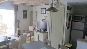Una cocina con una mesa de comedor, sillas, un televisor y un refrigerador.