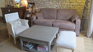 Una sala de estar con pared de piedra, un sofá, un sillón, una mesa de centro y una lámpara.