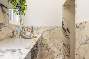 A modern kitchen with marble countertops, a sink, and a window. - Bailarina Historic Luxury House at Rua das Flores (Oporto)