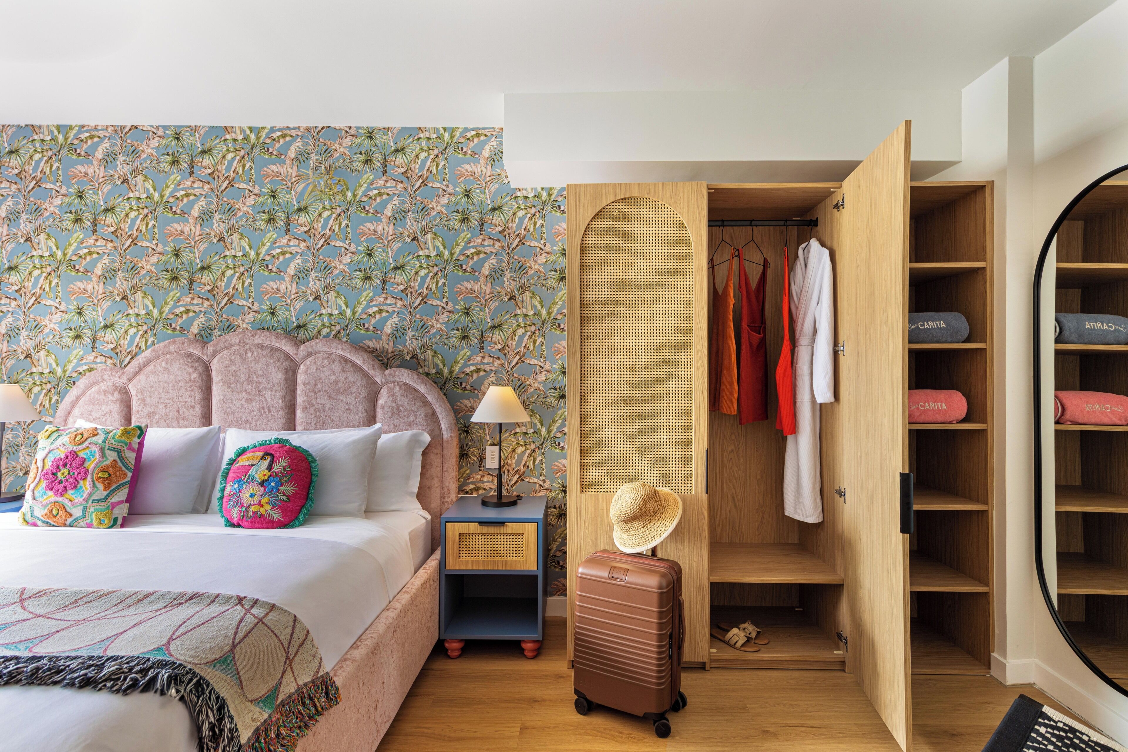 Un dormitorio con cama, mesita de noche, maleta, armario y espejo.