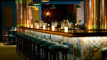 A bar area with a counter, stools, and hanging lights.