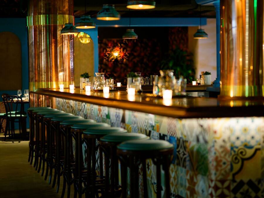 A bar area with a counter, stools, and hanging lights.