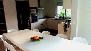 Una cocina moderna con armarios blancos, una mesa de comedor con sillas y un ventilador de techo.