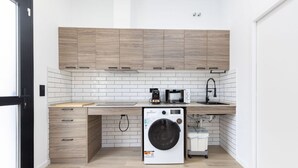 A compact kitchen with wooden cabinets, a built-in microwave, a washing machine, and a sink. - Travel Habitat Nou Mestalla 3 (Valencia)