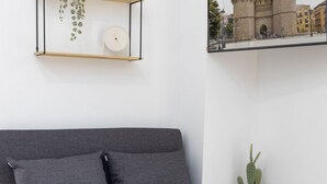 A modern living room with a grey sofa, a small plant, and a framed picture of a building. - Travel Habitat Nou Mestalla 3 (Valencia)