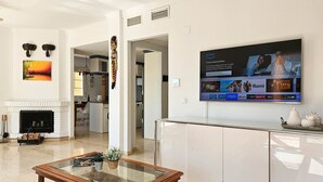Un soggiorno moderno con camino, un tavolino da caffè in vetro e un televisore a schermo piatto montato a parete.