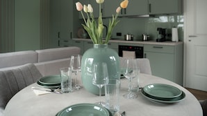 Een eettafel met een vaas tulpen, groene borden en glazen.