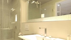 A modern bathroom with a glass-enclosed shower, a white sink, and a toilet.