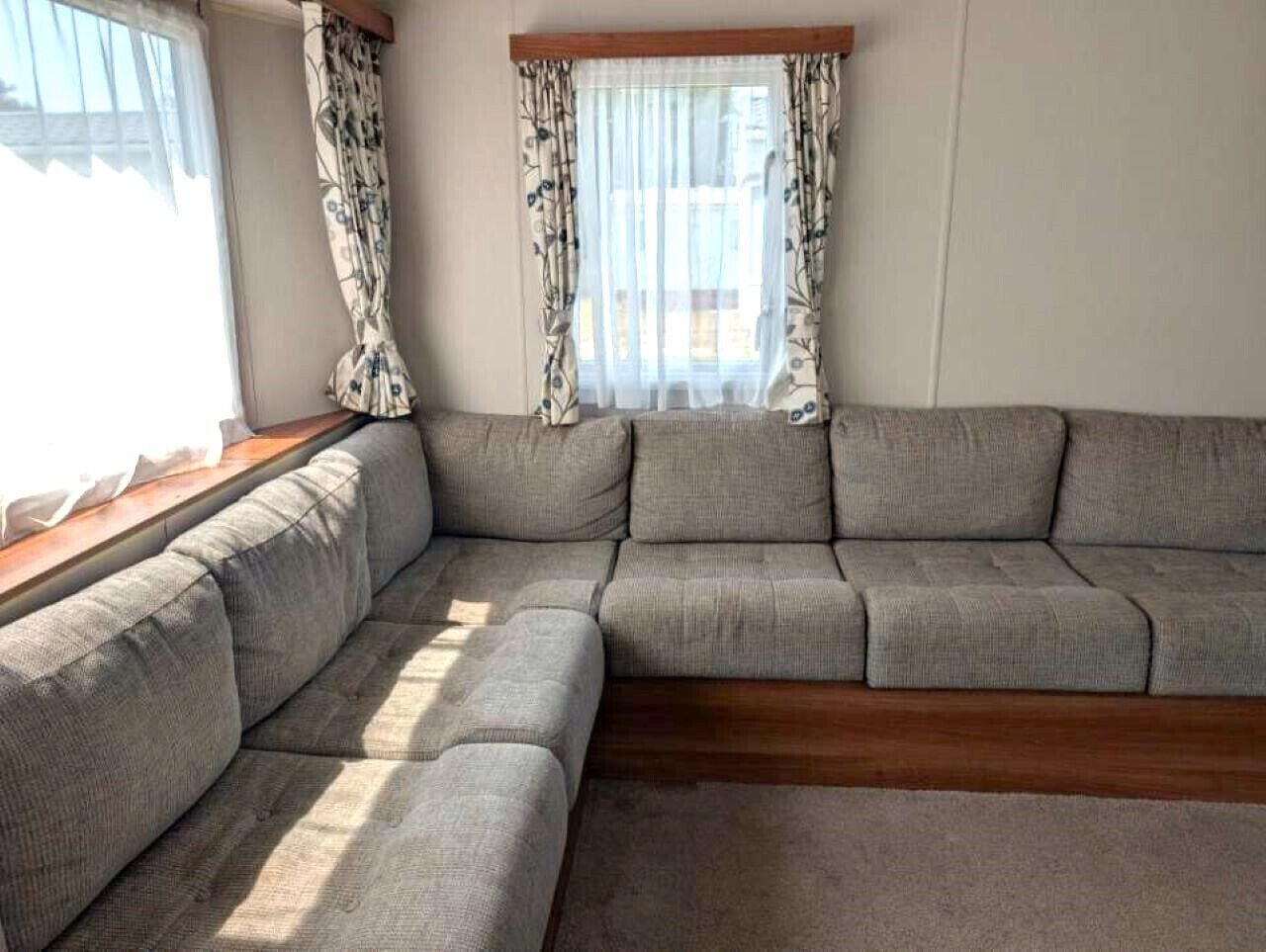 A sectional sofa in a room with a window and curtains.