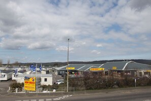 Lomakeskus, jossa on useita paikkoja asuntovaunuille ja -autoille, päärakennus, jonka kyltissä lukee »New Beach Holiday Park», ja kirkas taivas.