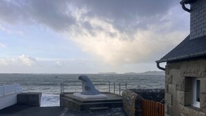 Un edificio de piedra con vista al mar y una escultura.