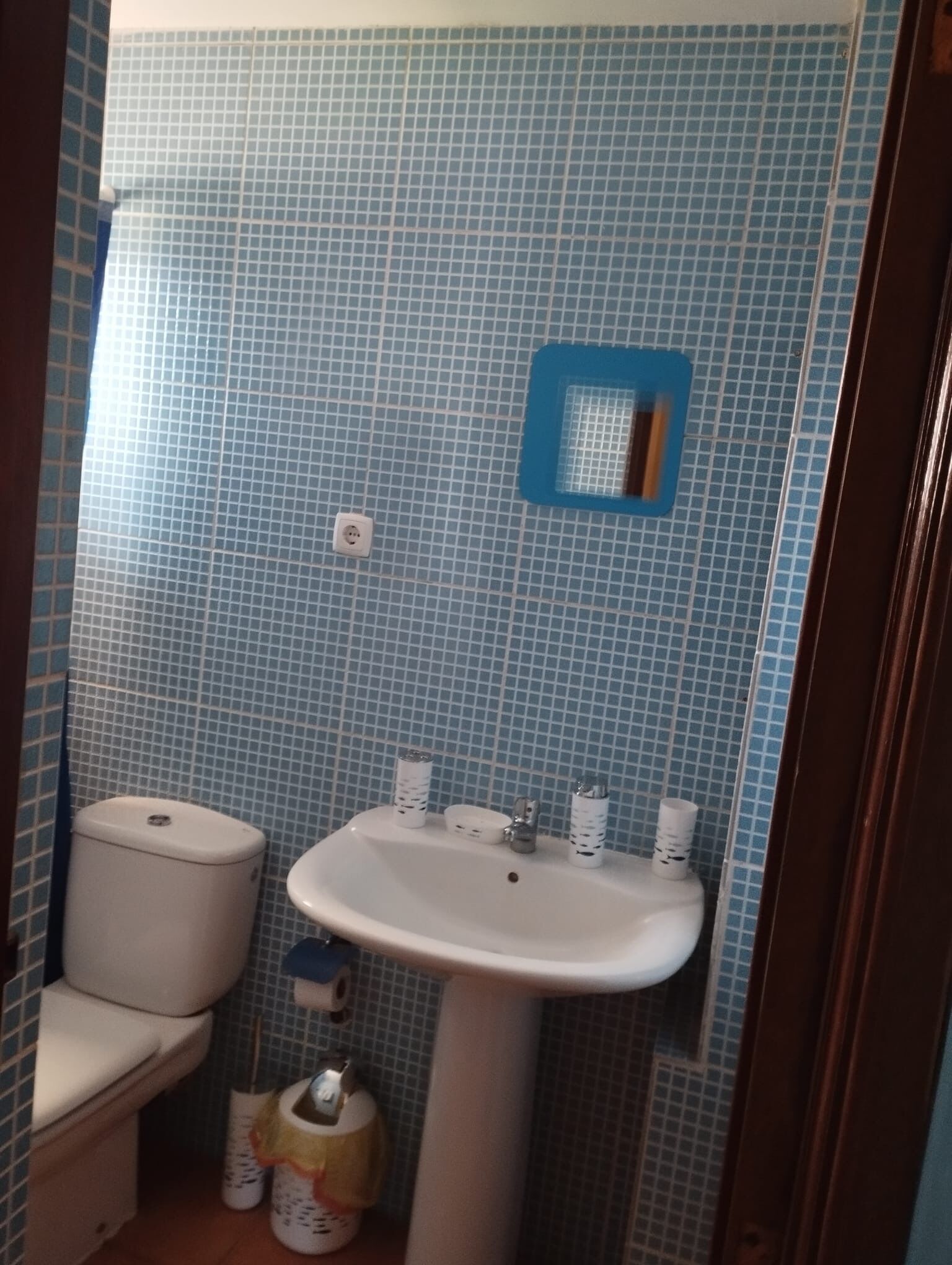 Un bagno con WC, lavandino e pareti piastrellate di blu.