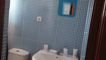 Un bagno con WC, lavandino e pareti piastrellate di blu.