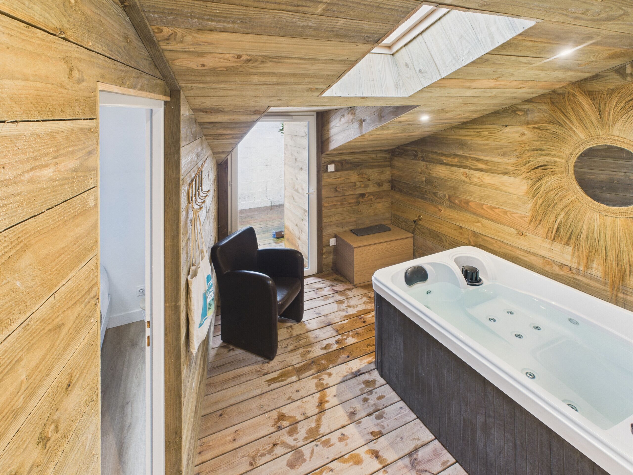 L’intérieur d’un chalet en bois, avec un bain à remous, une chaise et une petite boîte en bois.