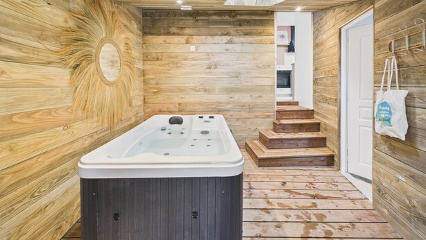 En inredning med träpanel, ett bubbelbadkar, en trätrappa och en vit dörr.