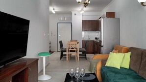 A modern living room with a flat-screen TV, a sofa, and a dining area with chairs and a table. - RentPlanet - Apartament Pomorska (Wrocław)