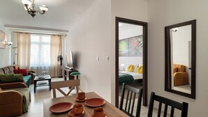 A modern living room with a dining area, a sofa set, a television, and a large mirror. - RentPlanet - Apartament Pomorska (Wrocław)