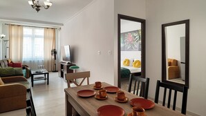 A modern living room with a dining area, a sofa set, a TV, and a dining table set with plates and cups. - RentPlanet - Apartament Pomorska (Wrocław)