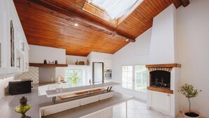 A modern kitchen with a wooden ceiling, white cabinetry, a central island, and a built-in oven. - Aile château de Saint-Sarnin - 14 pers, 5 chambres. piscine. parc & nature (Grisolles)