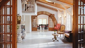 A spacious living area with a high ceiling, wooden beams, and a fireplace. There is a dining table with chairs and a sofa. - Aile château de Saint-Sarnin - 14 pers, 5 chambres. piscine. parc & nature (Grisolles)