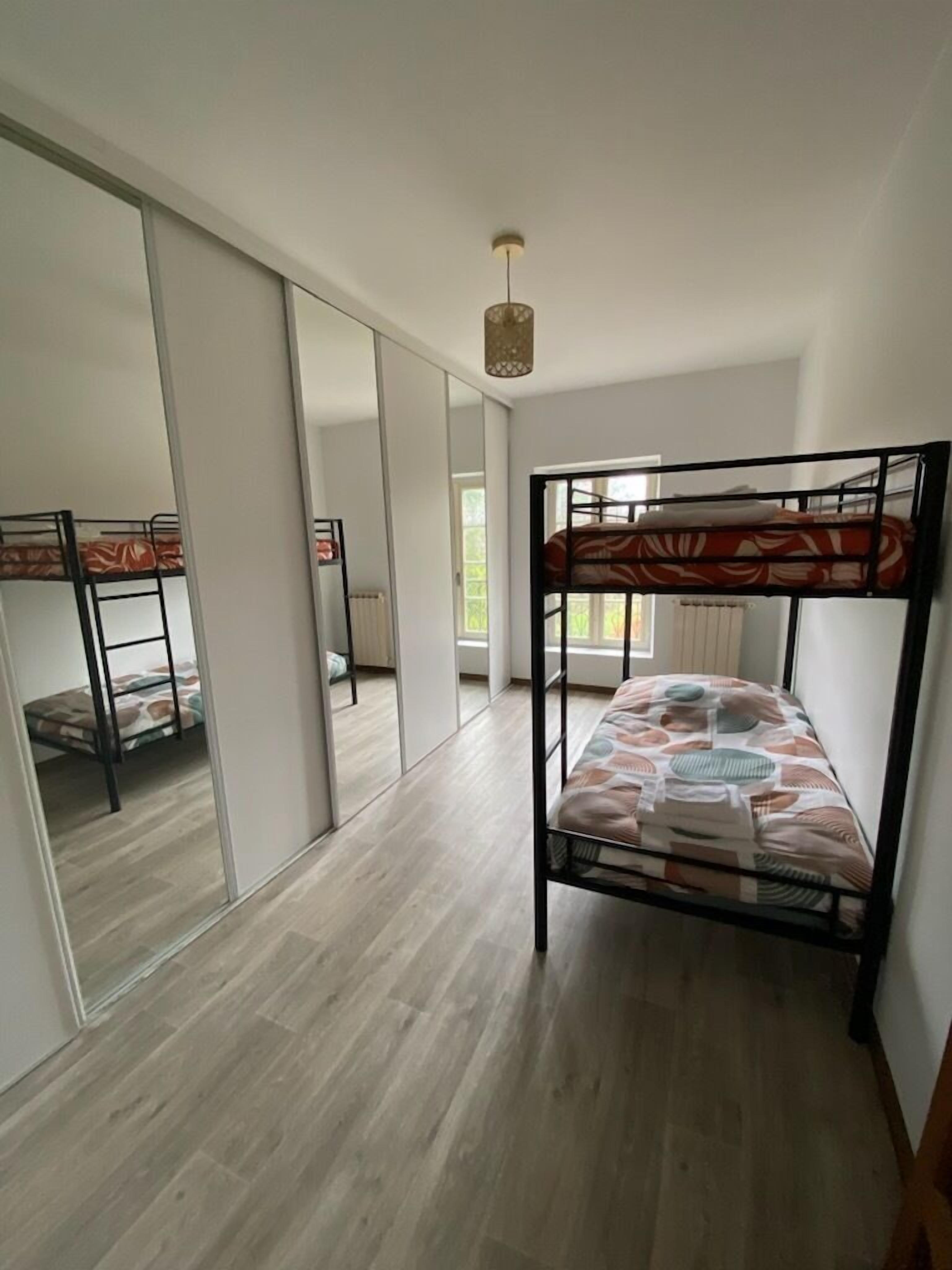 A room with a bunk bed, a sliding door, and a large mirror.