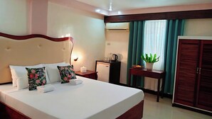 Ein Hotelzimmer mit einem großen Bett, einem Nachttisch, einer Lampe und einem Kleiderschrank.