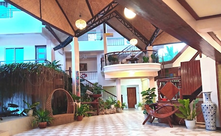 A spacious atrium with a checkered floor, a central staircase, and multiple potted plants.