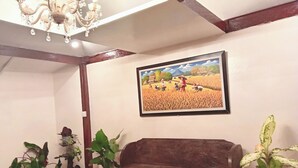 Ein Zimmer mit einer hölzernen Bank, Topfpflanzen, einem Chandelier und einem gerahmten Gemälde einer Landschaft.
