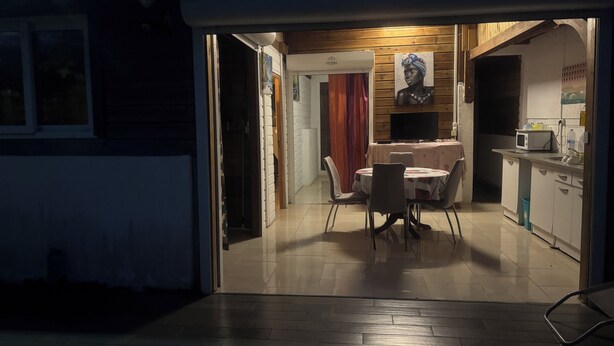 Un patio techado con una mesa y sillas, una cocina con microondas y un televisor.