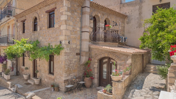 A stone building with a balcony, potted plants, and a small outdoor seating area. - Authentic Zakynthos Town Villa * 3 open-plan bedrooms * Sleeps <7 * Local Stay (Zakinthos)