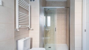 Ein modernes Badezimmer mit einer gläsernen Duschkabine, einer weißen Toilette und einem Handtuchhalter.