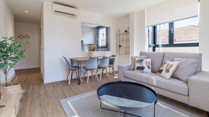 Ein modernes Wohnzimmer mit einer Couch, einem Couchtisch und einem Essbereich mit Stühlen.