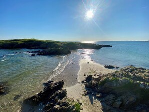 Paisaje costero con aguas cristalinas, costas rocosas y una vista distante del mar bajo un sol brillante.