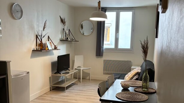 A modern kitchen with a refrigerator, a dining table with chairs, a TV, and a window with curtains. - Le Relais de David - Limoges (Limoges)