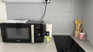 A kitchen with a microwave, a roll of paper towels, a coffee maker, and wooden utensils on the counter. - Le Relais de David - Limoges (Limoges)