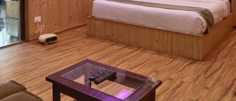 A bedroom with a wooden bed, a glass coffee table, and a ceiling with purple lighting.