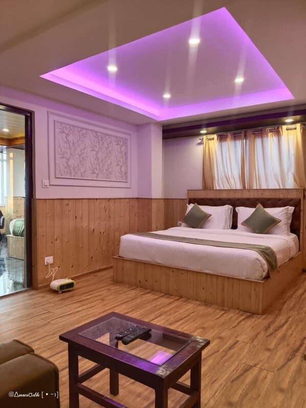 A bedroom with a wooden bed, a glass coffee table, and a ceiling with purple lighting. - WORMWOOD SYNERGY NEW MANDALA (Darjeeling)