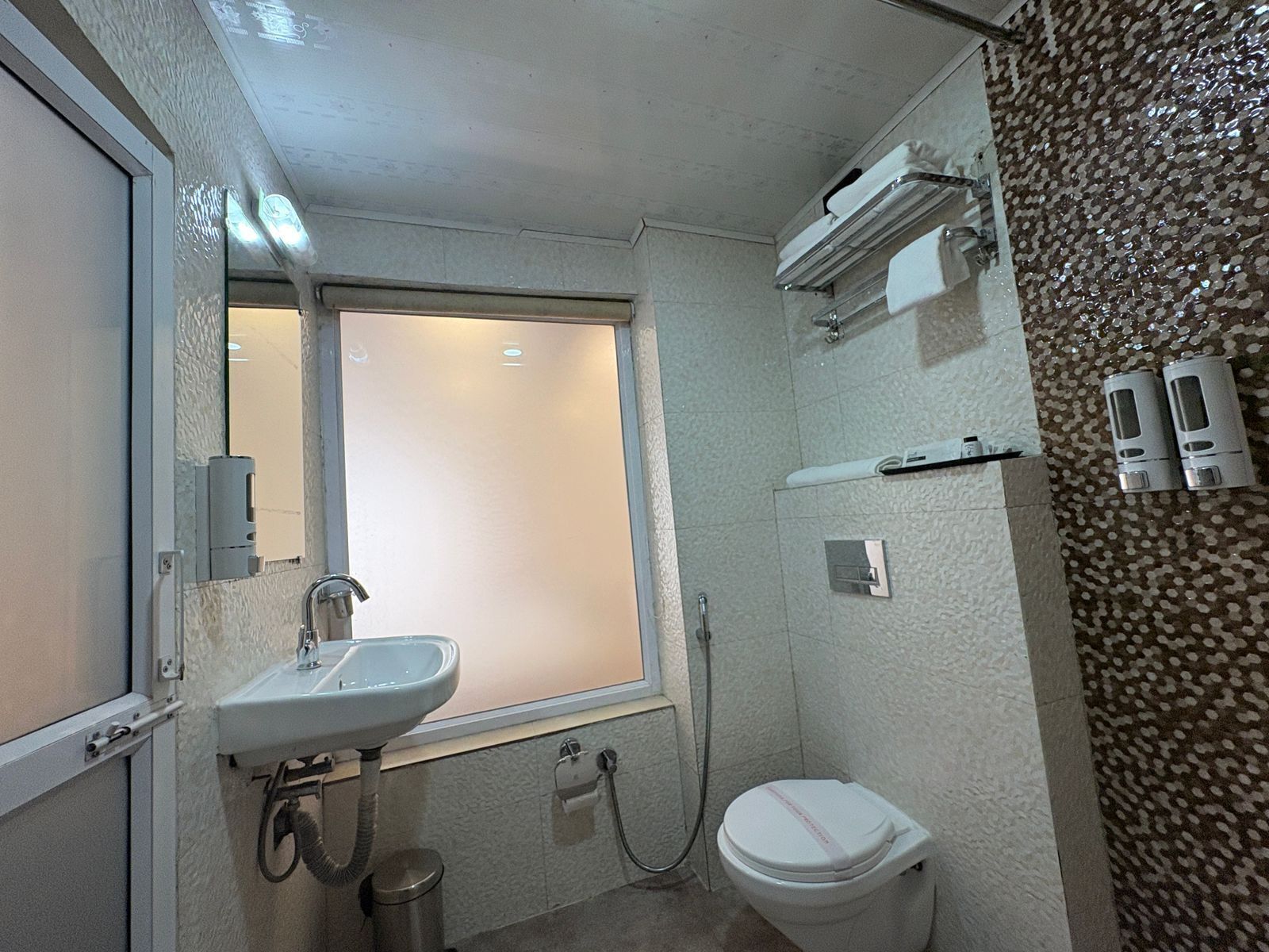 A small bathroom with a sink, toilet, and window.