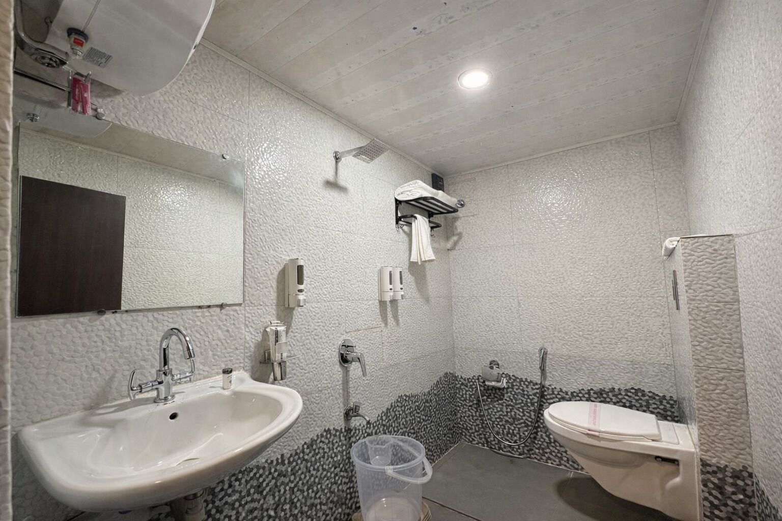 Een badkamer met een wit wastafelmeubel, een spiegel, een handdoekhouder en een douchehoek.