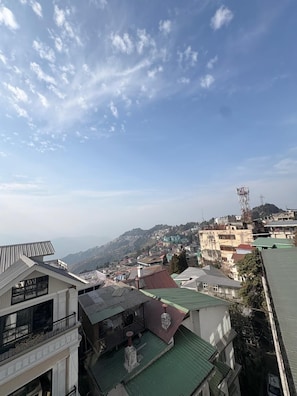 A residential area with buildings, a prominent tower, and a mountainous backdrop. - WORMWOOD SYNERGY NEW MANDALA  (Darjeeling)