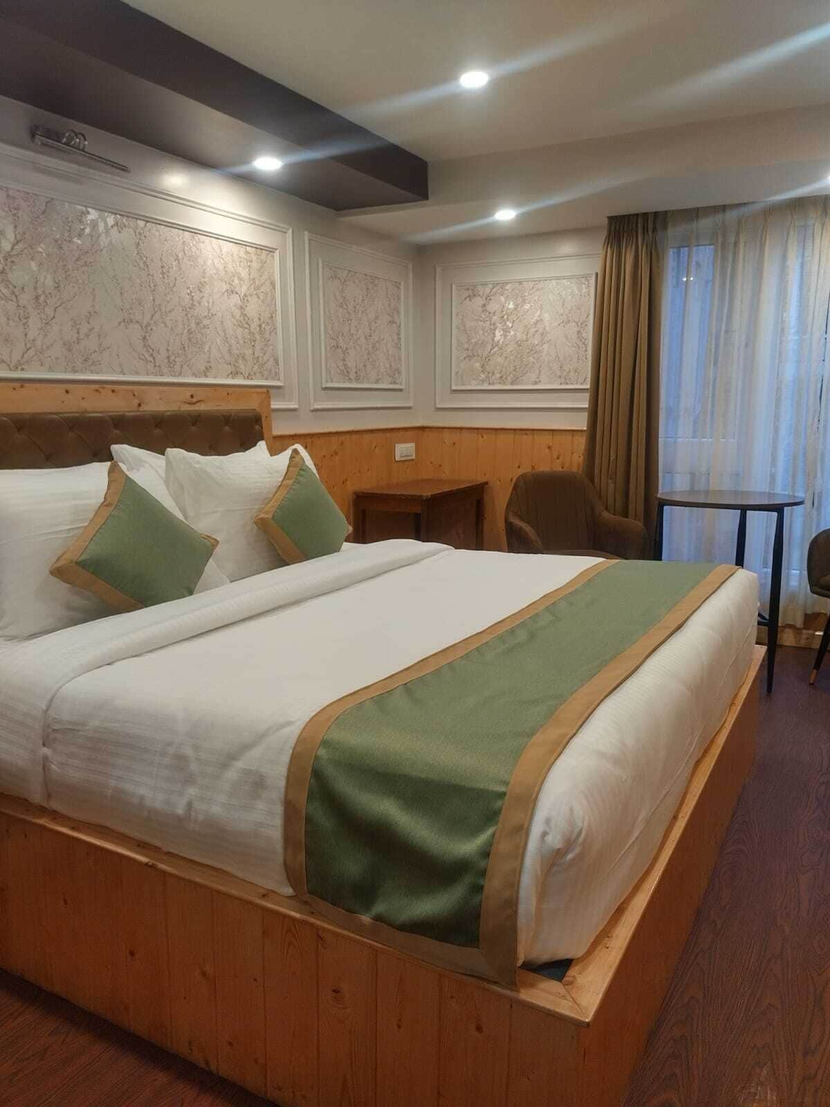 A hotel room with a large bed, wooden headboard, and a small desk.