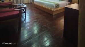 A bedroom with a sloped ceiling, wooden flooring, a bed with pillows, a bedside table, and a window with curtains. - WORMWOOD SYNERGY NEW MANDALA  (Darjeeling)