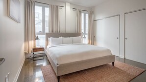 Ein modernes Schlafzimmer mit einem großen Bett, einem Nachttisch, einer Lampe und einem Kleiderschrank.