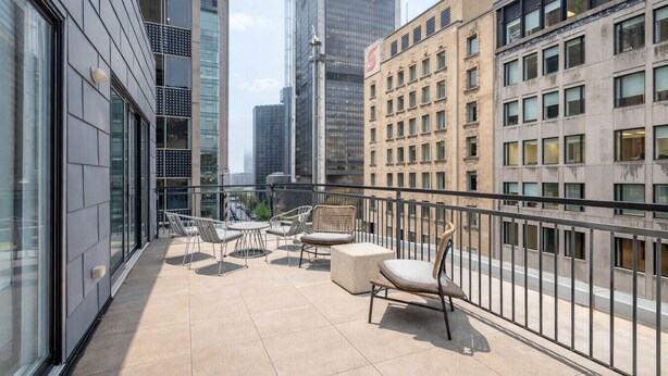 Ein Balkon mit Sitzgelegenheit, Blick auf eine Stadtlandschaft und moderne Gebäude.