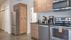 Une cuisine moderne dotée d’appareils électroménagers en acier inoxydable, de meubles en bois et d’un four encastré.