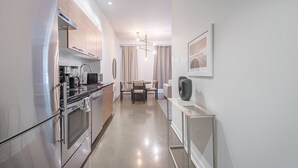 A modern kitchen with stainless steel appliances, a dining area with a table and chairs, and a minimalist decor. - Chic Old Montreal Apt with Terrace (Montréal)