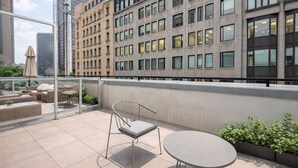 A rooftop terrace with outdoor seating, a glass balustrade, and a view of surrounding buildings. - Chic Old Montreal Apt with Terrace (Montréal)