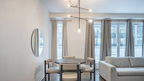 A modern living room with a round table and four chairs, a grey sofa, and a large mirror on the wall. - Chic Old Montreal Apt with Terrace (Montréal)