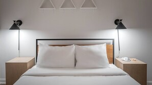 A neatly made bed with white linens, a wooden headboard, and two bedside tables with lamps. - Chic Old Montreal Apt with Terrace (Montréal)